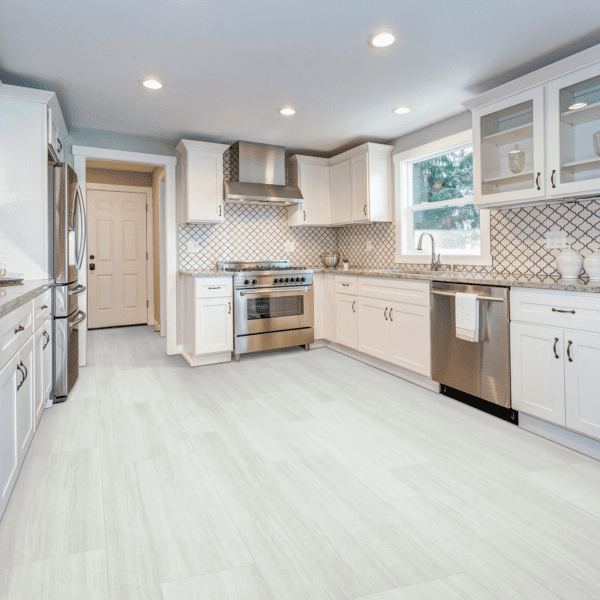 A kitchen with white cabinets and tile floors.