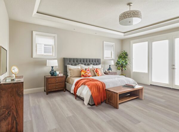 A bedroom with a bed, nightstand and window.