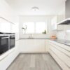 A kitchen with white cabinets and wood floors.