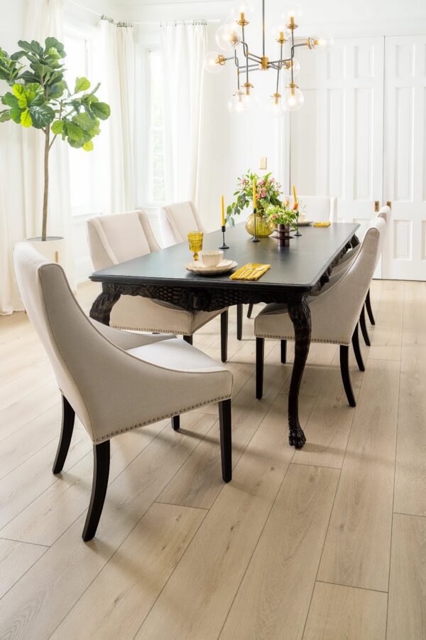 A dining room table with eight chairs and a vase of flowers.